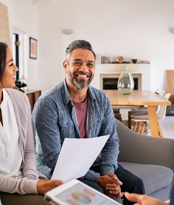 Three people gather around a sofa to discuss the pros and cons of a living trust.