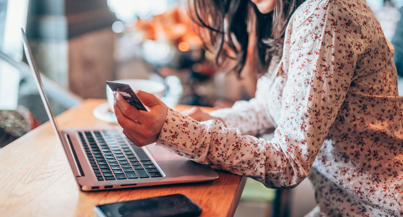 Woman holding credit card looking at laptop