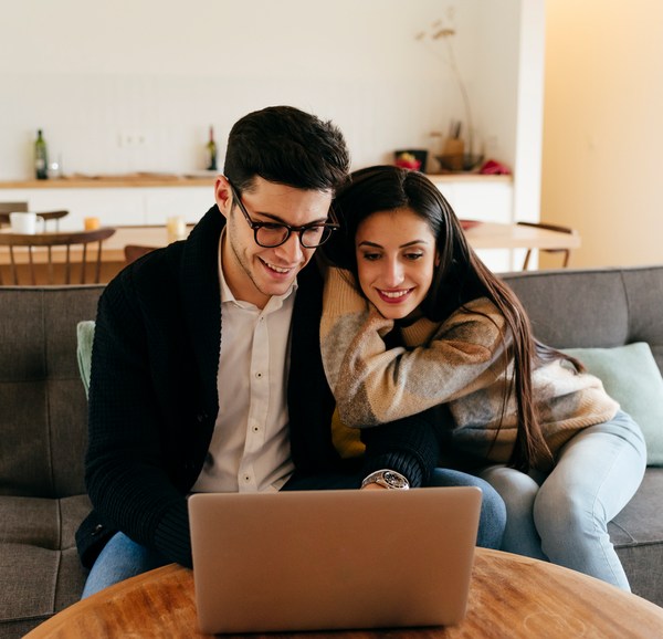 Man Using Laptop with Partner On Sofa