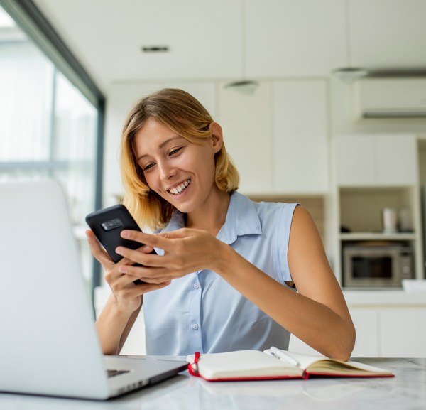 Woman smiling looking at phone and working from home