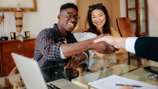 couple-shaking-hands-with-business-person