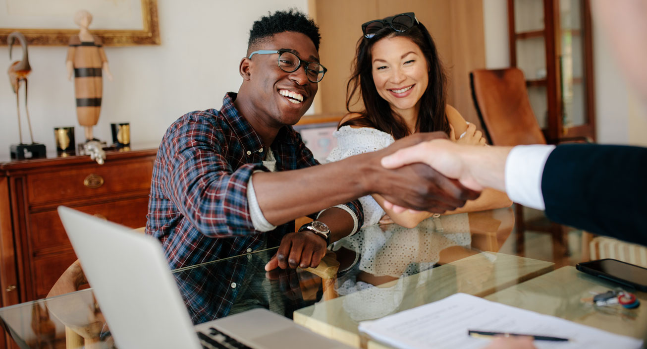 couple-shaking-hands-with-business-person