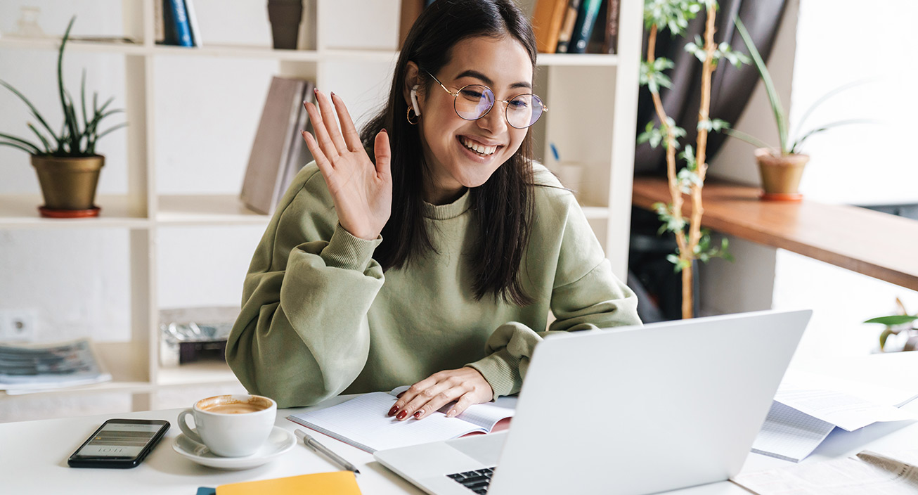 woman-smiling-and-waving-to-video-call-on-laptop