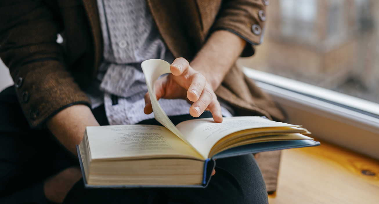 close-up-of-person-in-blazer-turning-the-page-of-a-book