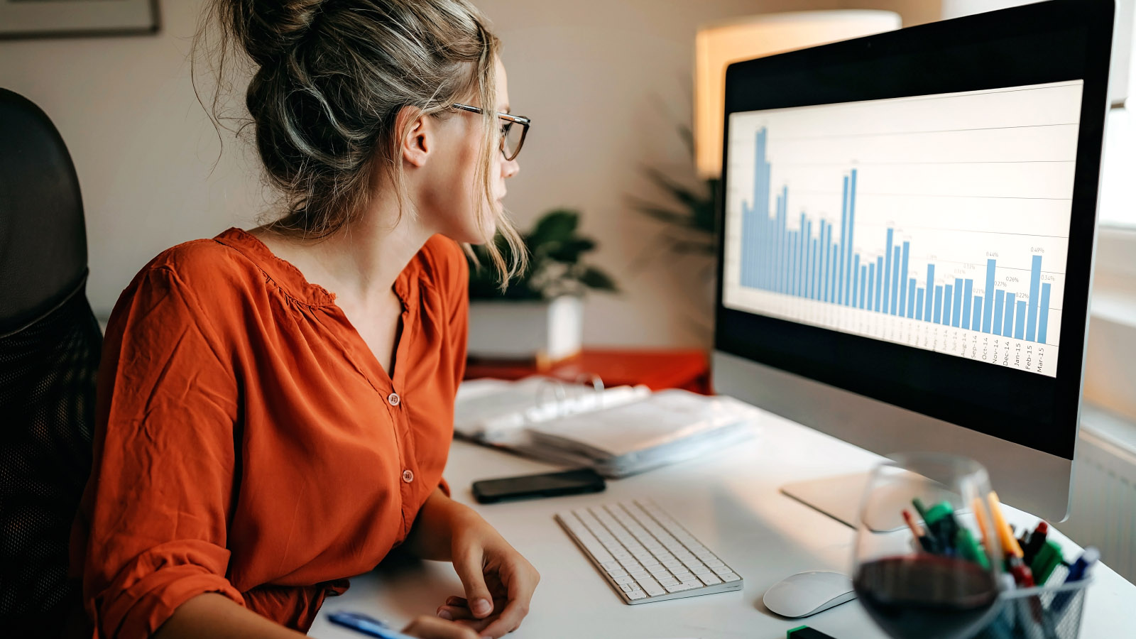 A woman sits at a desk and looks at data comparing a bull vs bear market on her computer.