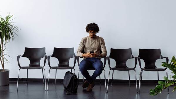 man-sitting-waiting-room-using-phone