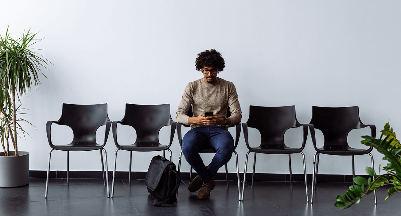 man-sitting-waiting-room-using-phone