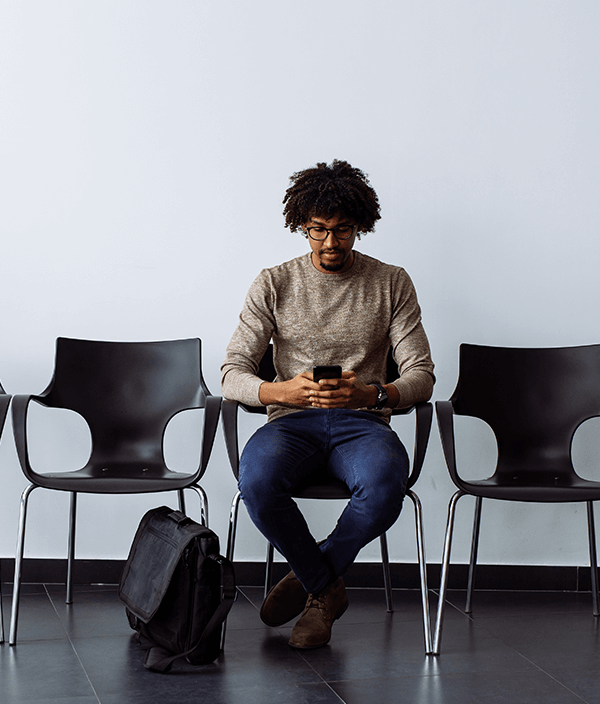 man-sitting-waiting-room-using-phone