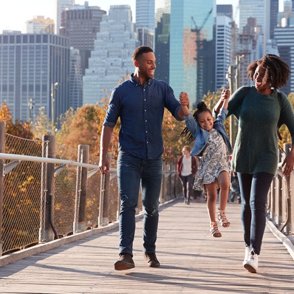 family walking on footbridge in front of cityscape