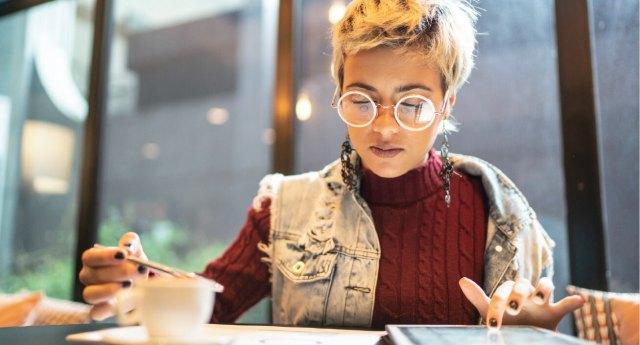 A woman sits on a table and looks at her bank statement, indicating she wants to develop better money habits.