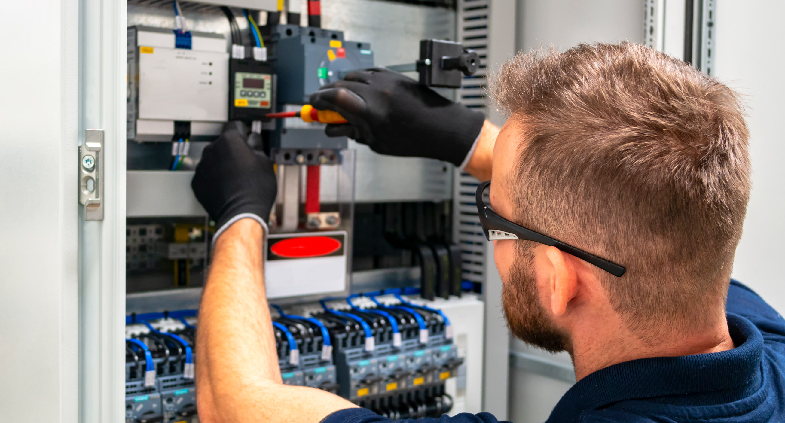 An electrician, one of the highest paying trade jobs, fixes a power box.