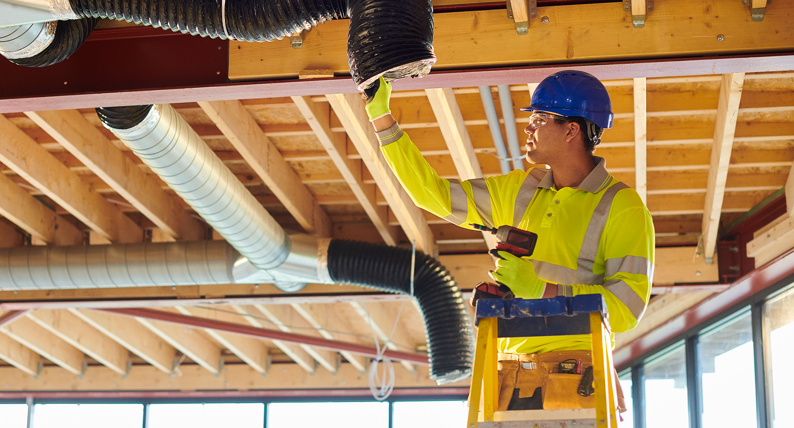 An HVAC technician, one of the highest paying skill trade jobs, works on air ducts of an office building.