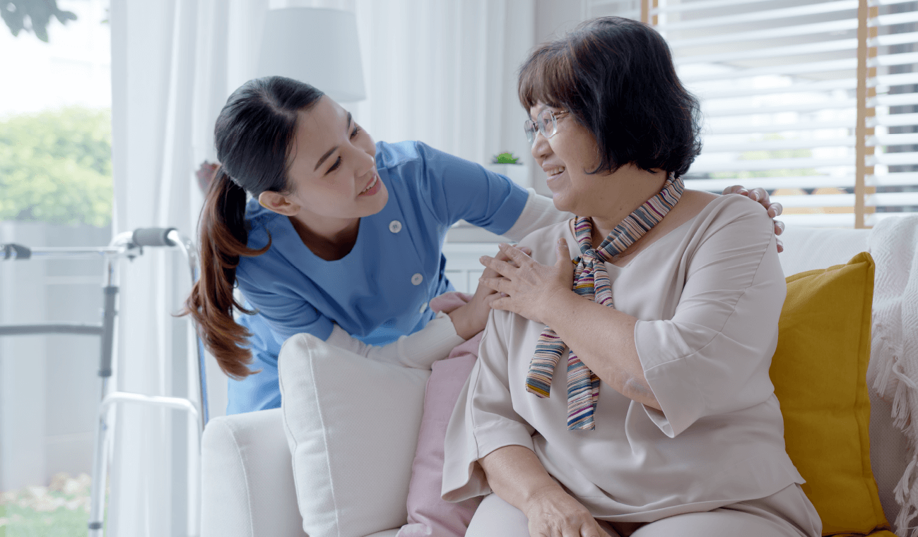 An Asian woman in a scrubs comforts an older Asian woman, indicating she might be a caregiver, one of the best self-employed jobs.