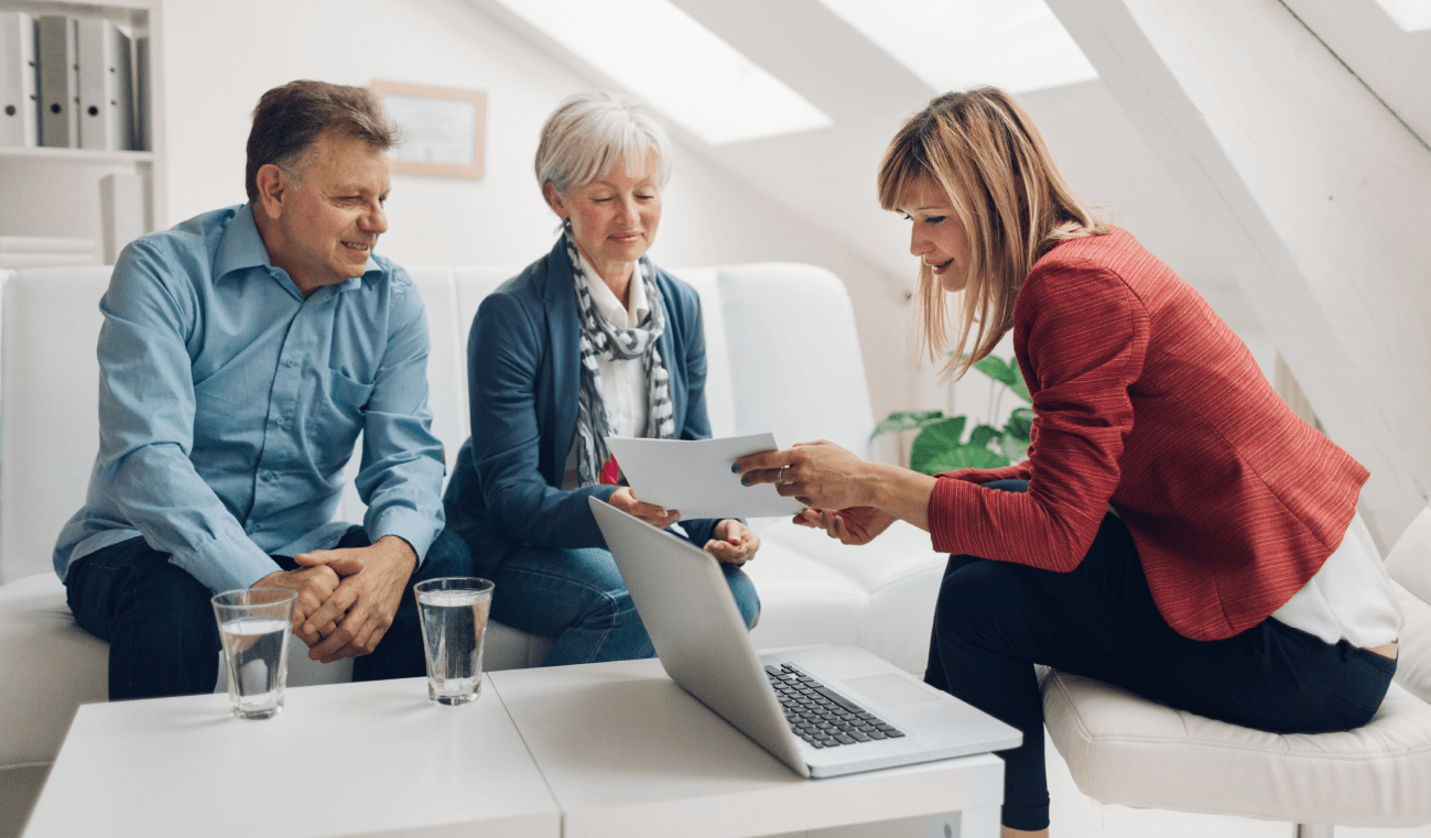 An older couple sits down with a woman in a red blazer, indicating they may be meeting a financial advisor, one of the best self-empoyed jobs.