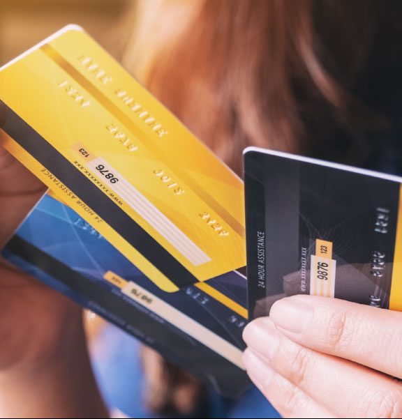 A woman holds three credit cards and decides whether she’d like to choose a secured vs. unsecured credit card.