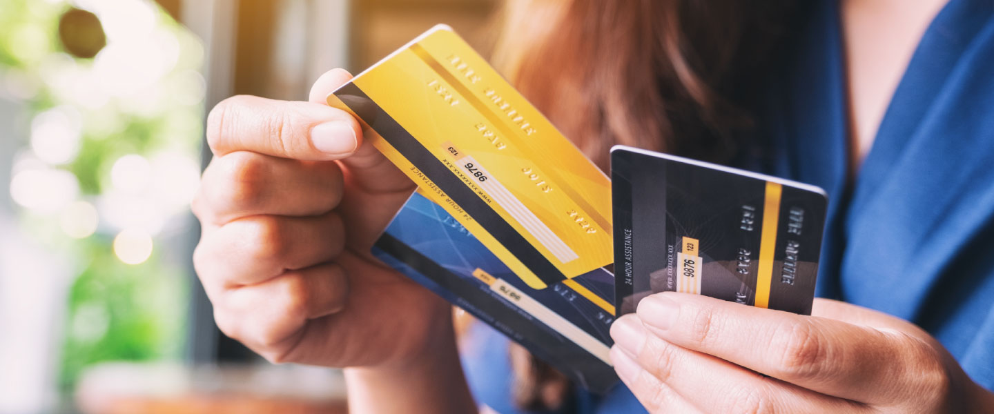 A woman holds three credit cards and decides whether she’d like to choose a secured vs. unsecured credit card.