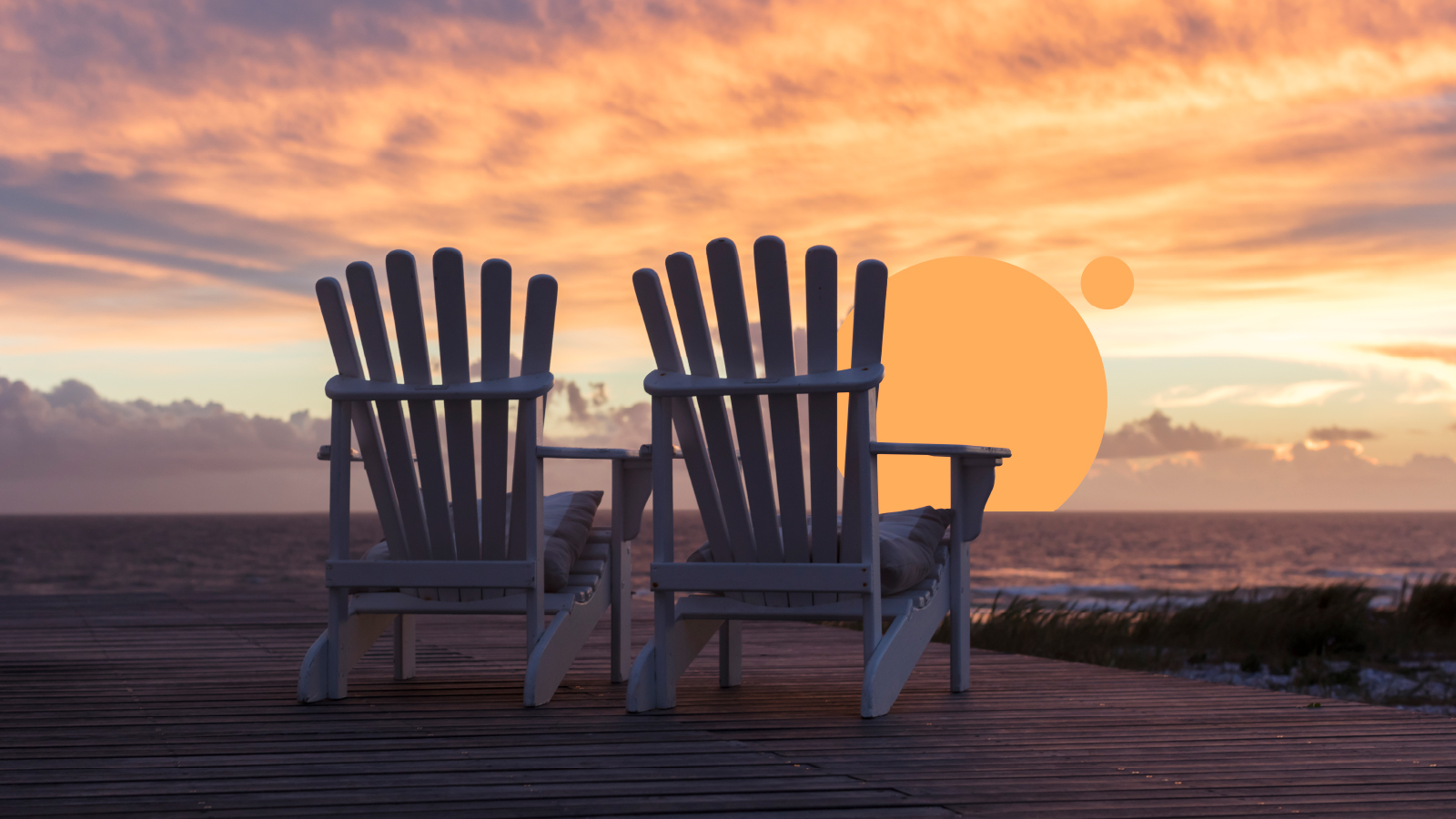 Two empty Adirondack chairs in front of a beautiful sunset